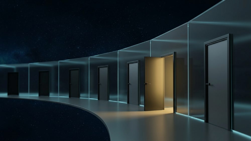 A corridor of dark glass doors with one open door spilling warm light